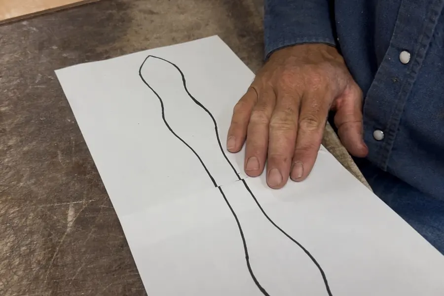 A hand beside a slobber leather pattern drawn out on paper