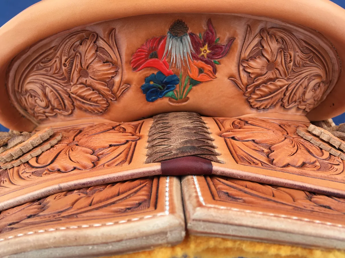 Saddle seat with color-tinted floral carving across the jockeys